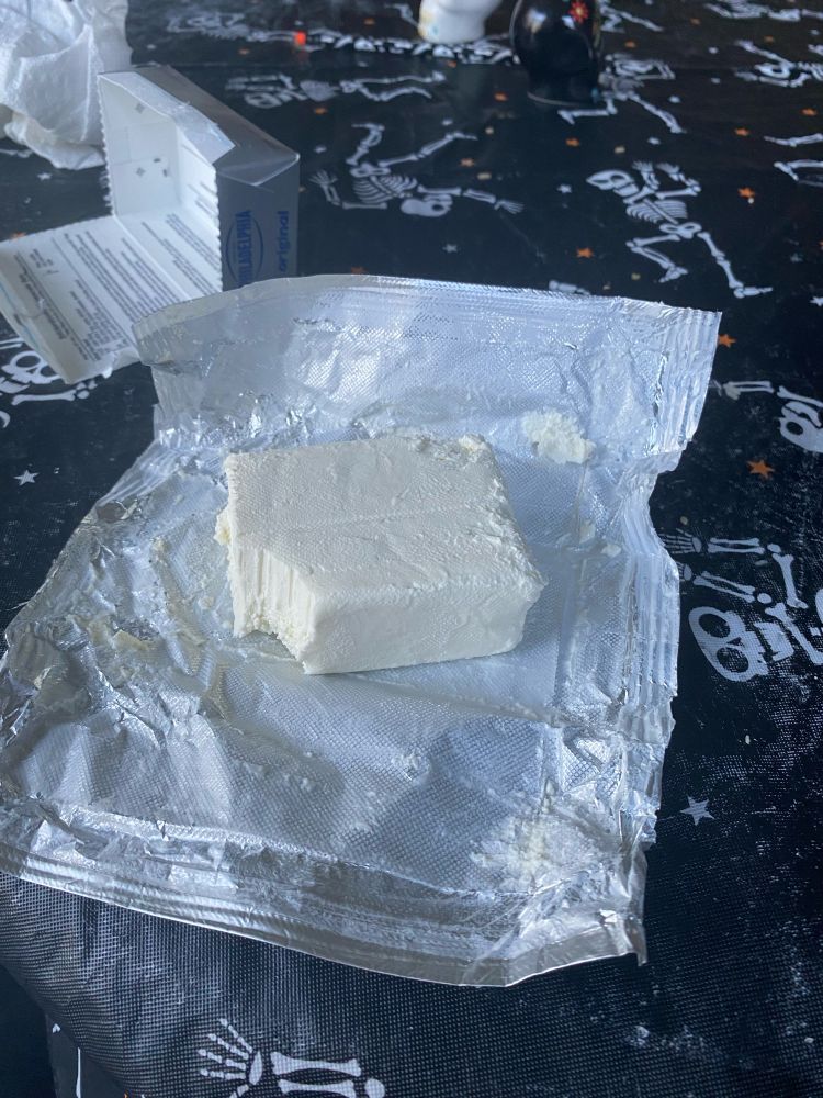 A block of cream cheese with a bite taken out of it