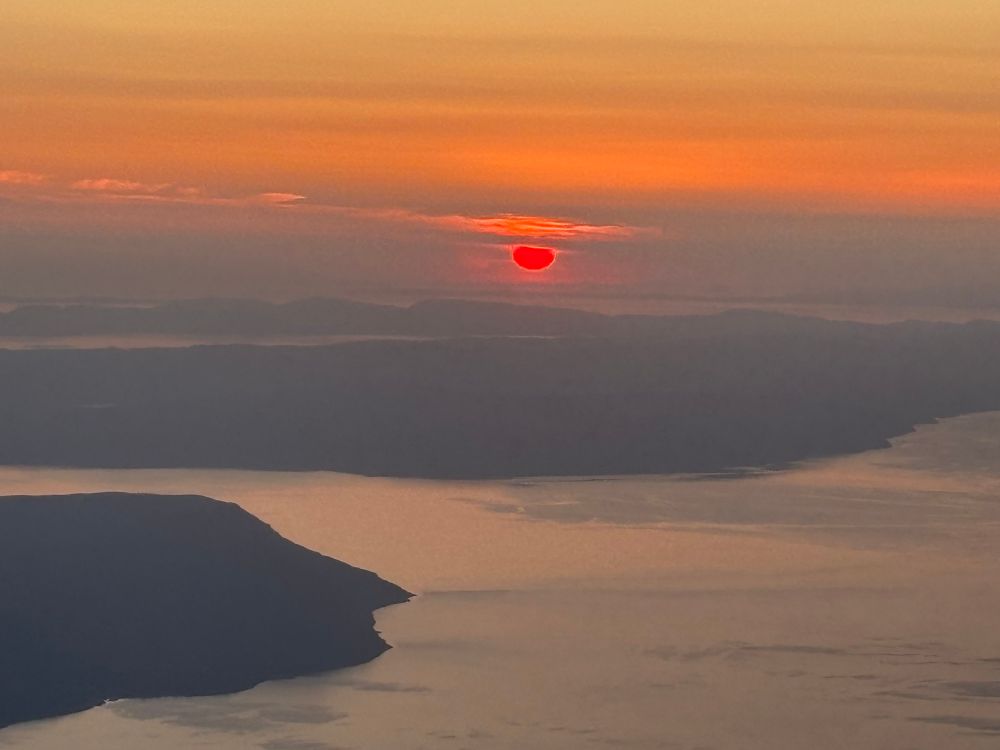 Red sun in an orange glow over sea and land from an aeroplane 