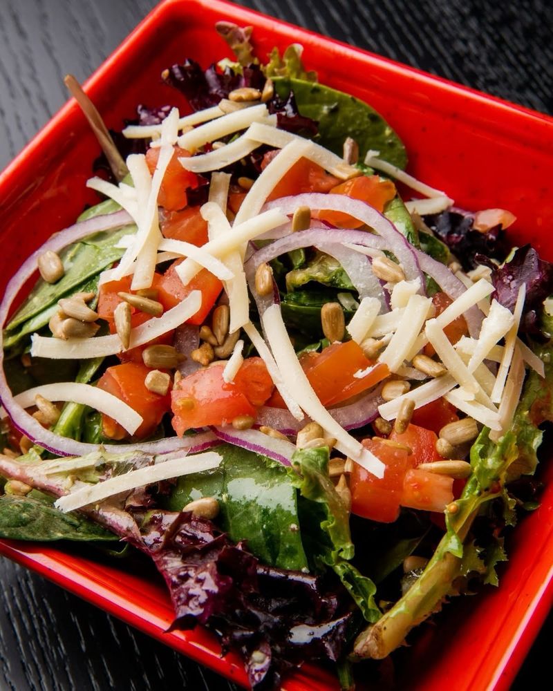 Image of a salad topped with tomatoes, cheese, and corn. 