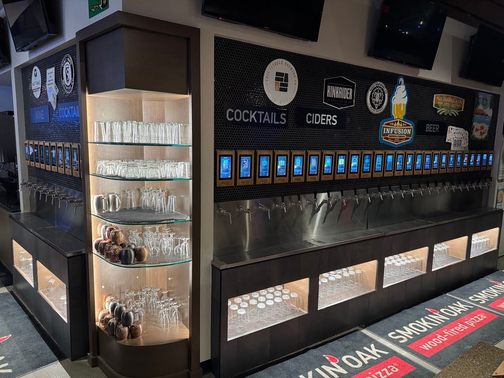 Image of a wall of 30+ self serve taps with small screens above. 