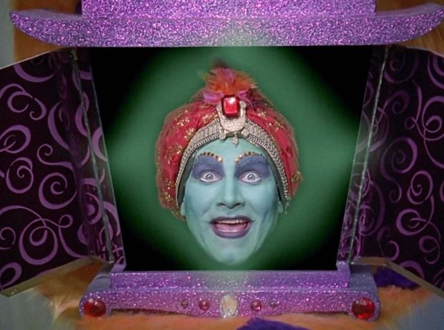 Jambi from Peewee's Playhouse, a disembodied genie head in an elaborate box. Green skin with purple eyeshadow, red turban, red sequin eyebrows. 