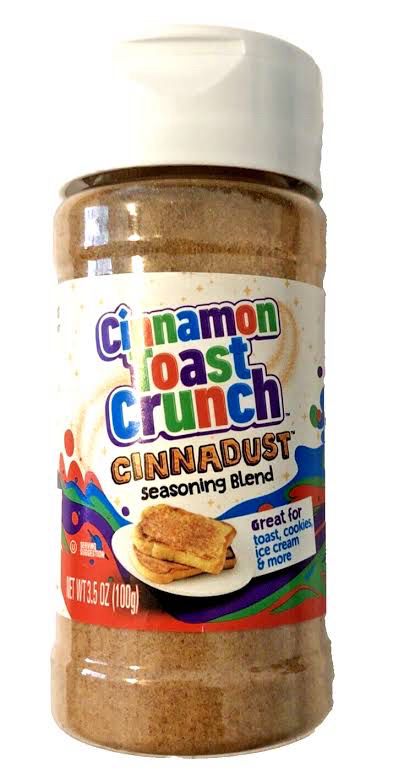 Plastic container of Cinnamon Toast Crunch Cinnadust. Clear container with light brown powder in it. 