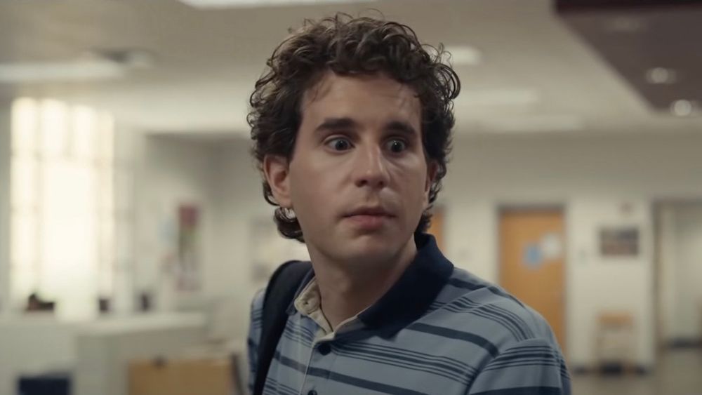 Image of Ben Platt from Dear Evan Hansen's movie adaptation. He's a 27 year old man dressed and styled like a high schooler. Blue polo striped with navy, and. Navy collar. 