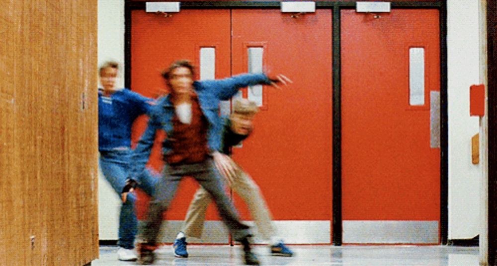 three people are dancing in a hallway with red doors