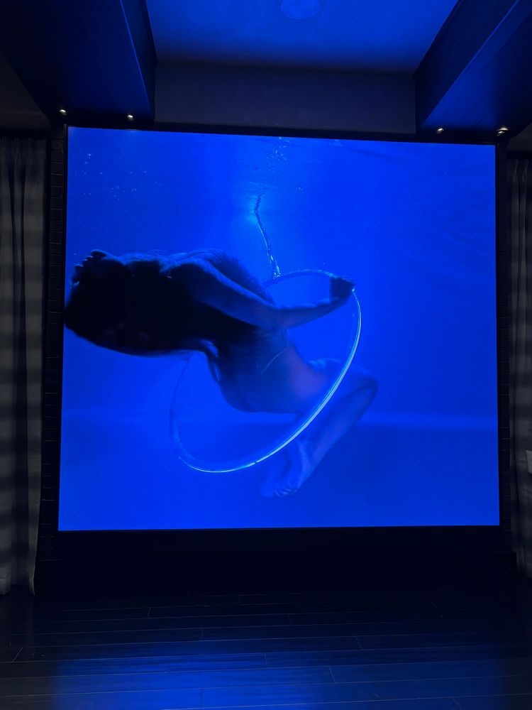 Giant big screen tv from the ceiling to the floor of a girl swimming with a hula light 