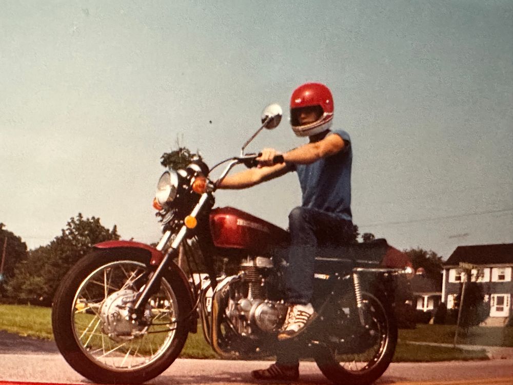 Helmeted man on a red motorcycle photographed from a low angle.