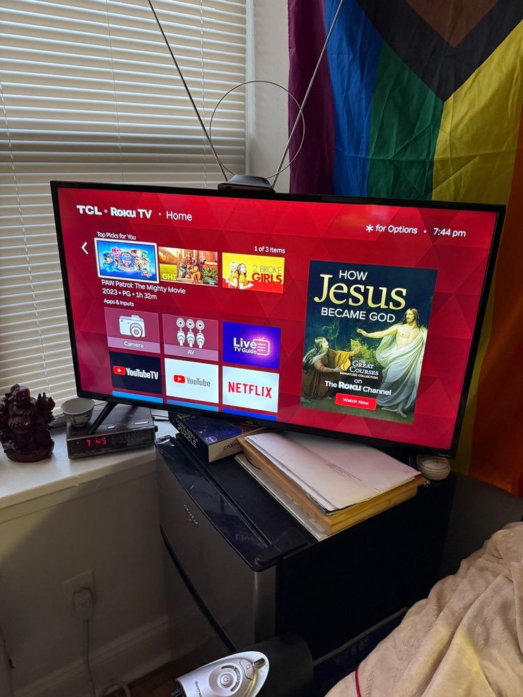 My “smart” tv with the Roku main menu on showing an ad for a “the great courses - on the Roku channel: how Jesus became god” programme 