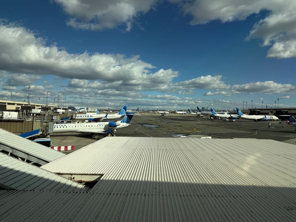 View of the tarmac in newark airport, with United planes at gates and a partly cloudy sky