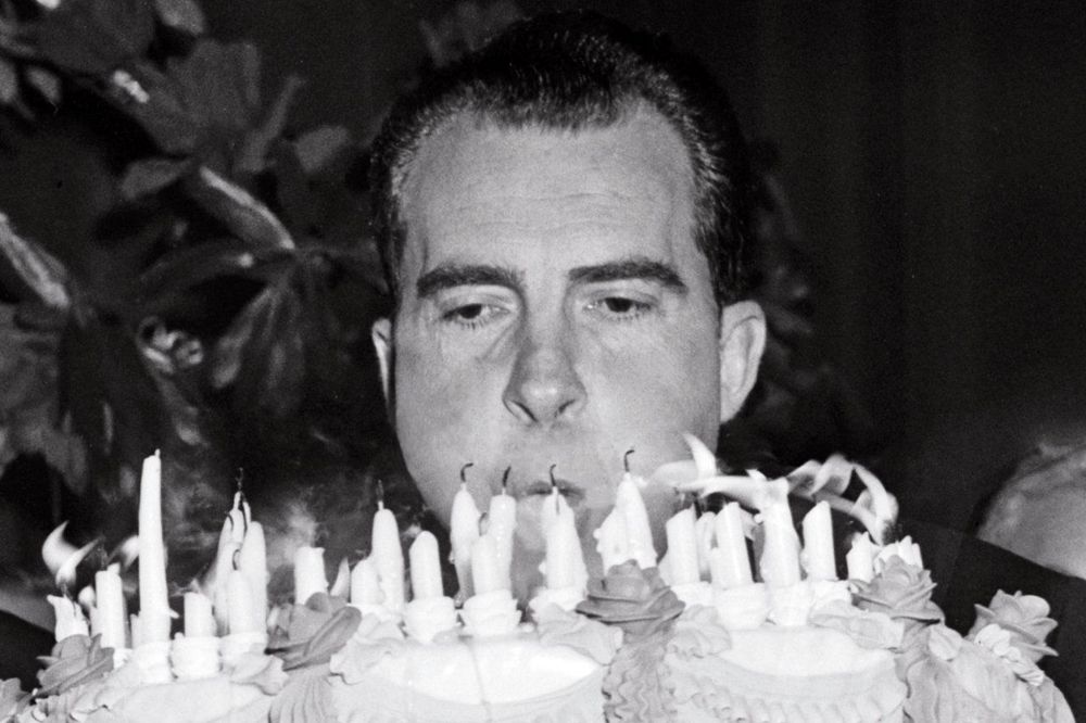 nixon blowing out birthday candles but his head is like below the cake