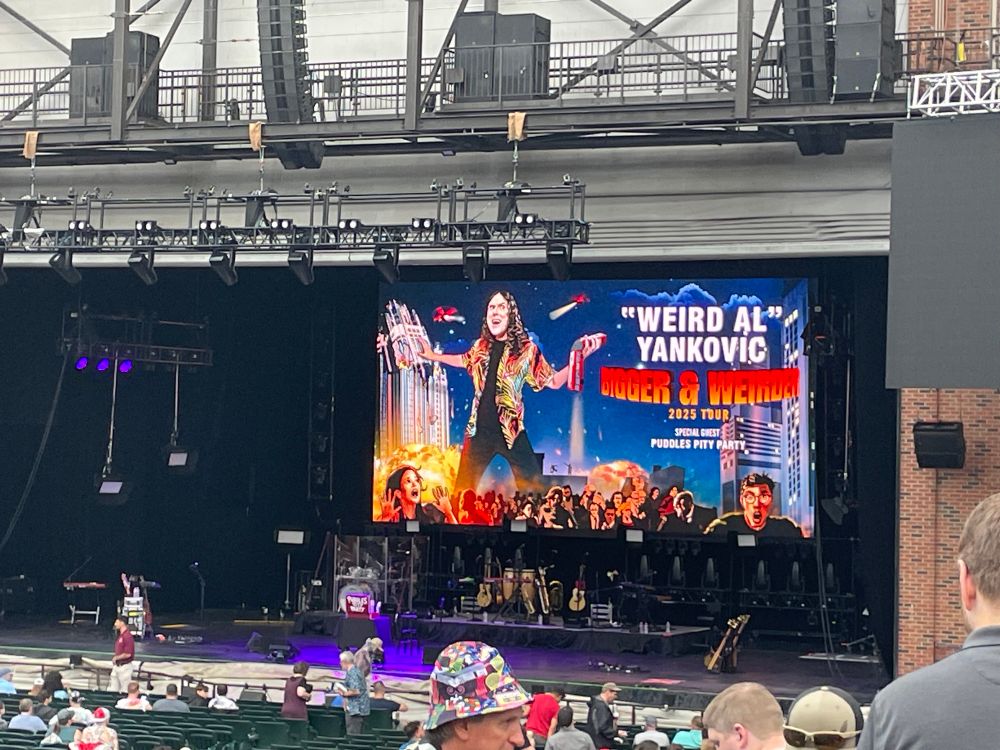 A picture of the stage at Starlight Theatre in Kansas City with the Weird Al tour banner behind the band instruments.