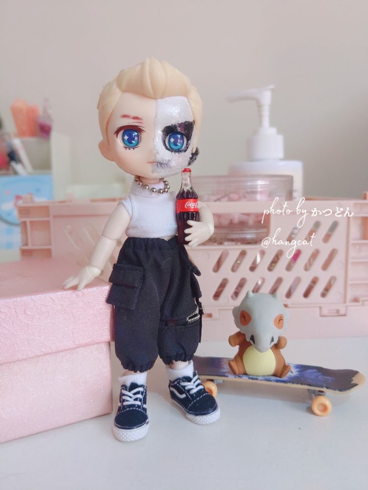 same doll, holding a mini CocaCola, alongside a mini karakara pokemon.