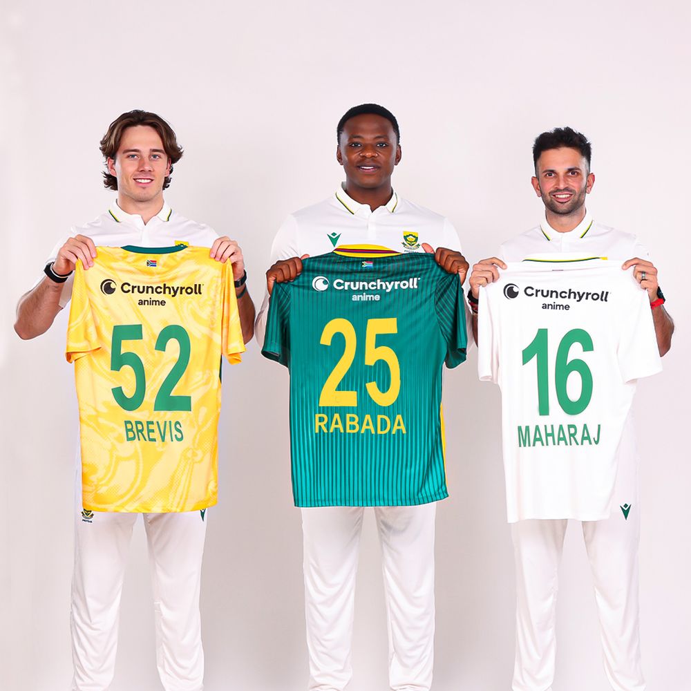 South African cricket players Dewald Brevis, Kagiso Rabada, and Keshav Maharaj show off shirts with Crunchyroll anime as a sponsor on the back.