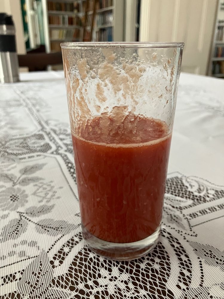 Partially filled glass ot tomato juice.