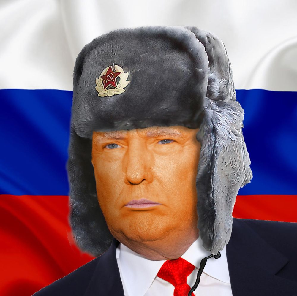 Very orange person wearing Soviet military ushanka and standing in front of Russian flag