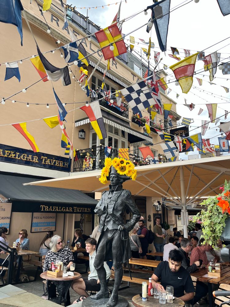 Statue of Horatio Nelson outside a pub in Greenwich. His head is adorned with sunflowers 