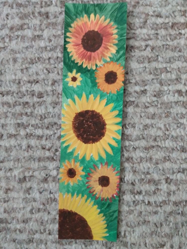 A bookmark painted with various sizes of sunflowers on a green background