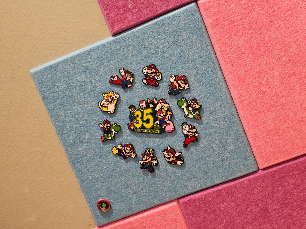 On one of the blue tiles is a set of 10 Mario pins with key art from each major game in the series. They form a circle around a large central pin celebrating the 35th anniversary of Super Mario Bros.