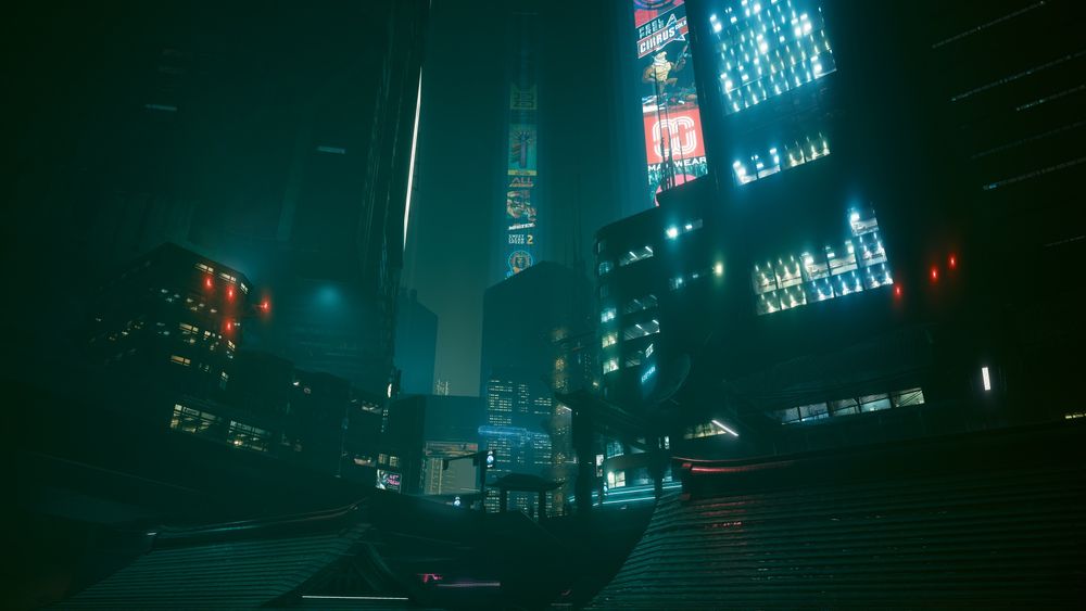 A hazy screenshot of Cyberpunk 2077. A city scape rises up over the tops of traditional Japanese buildings. There is a blue to the photo. Neon and red lights cut through the night. Ad scrolls beam into the sky. 