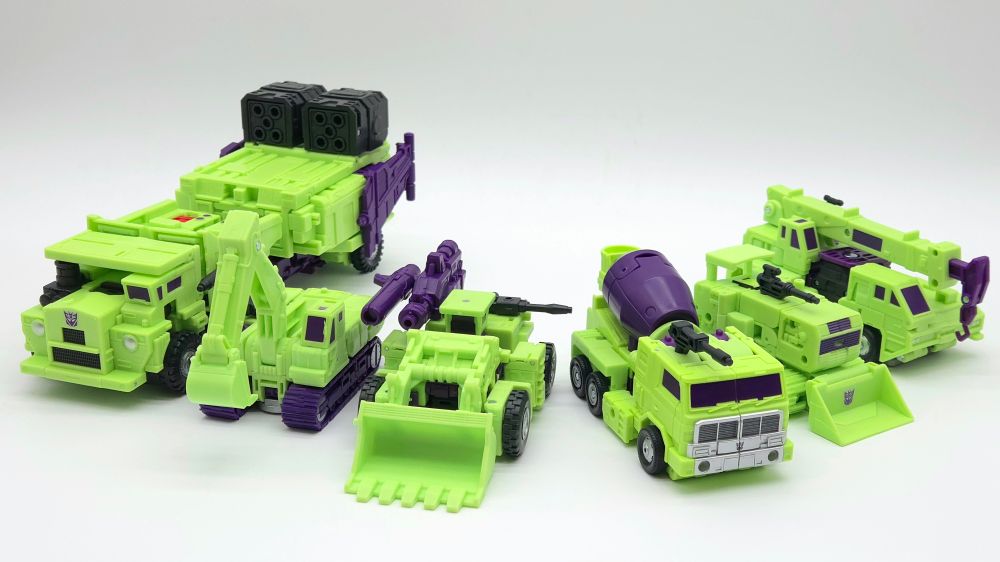Studio Series 86 Constructicons in their vehicle modes lined up in a row, from left to right, Long Haul, Scavenger, Scrapper, Mixmaster, Bonecrusher, and Hook.