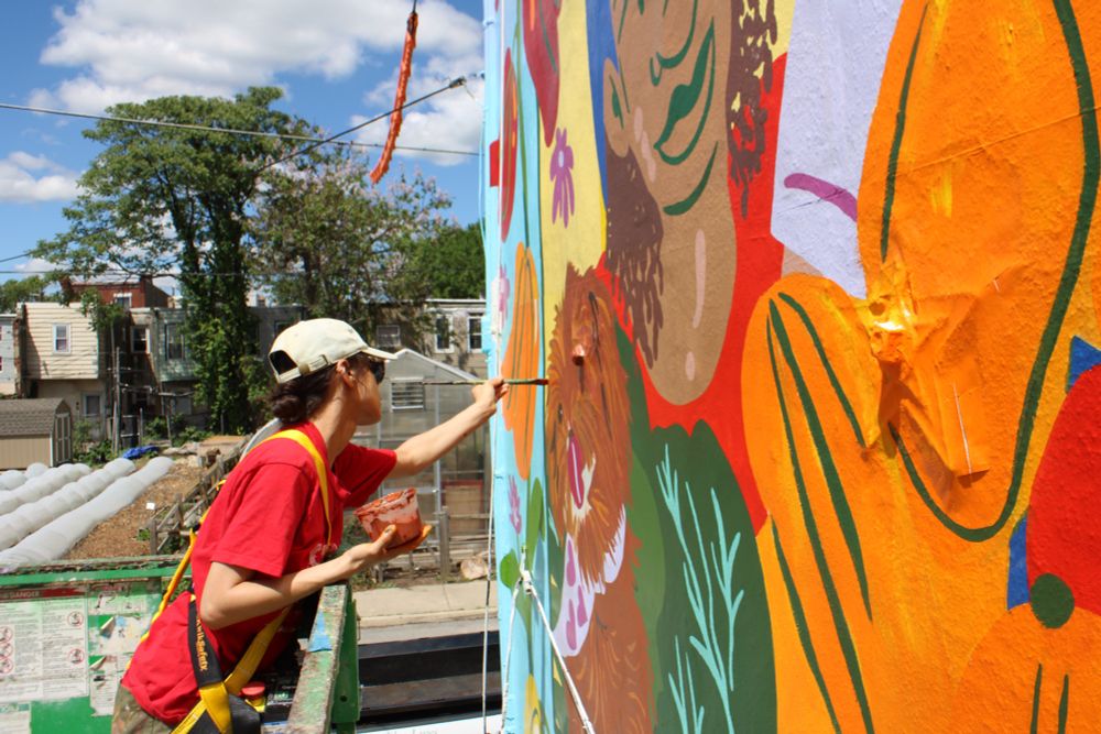 Artist Cindy Lozito painting the hair of a cute dog named Jake in the Sanctuary Farm mural 