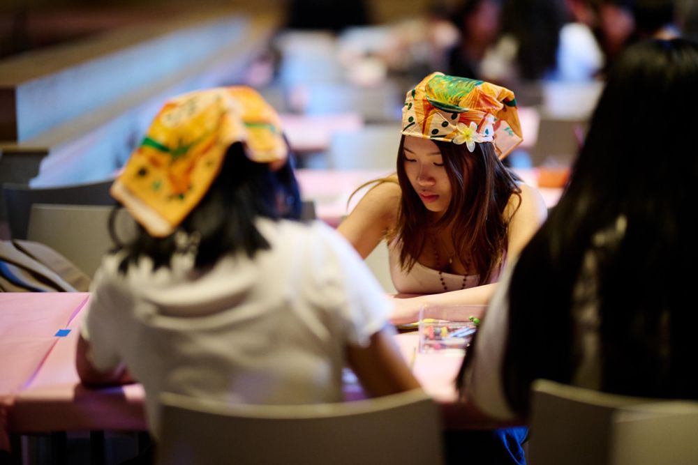 Two young artists wearing the Fabric of Belonging scarf while they draw their own scarf designs