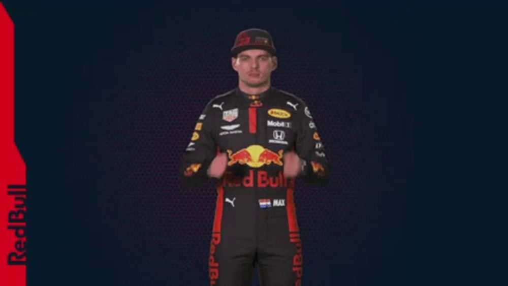 a man in a red bull racing suit is clapping his hands