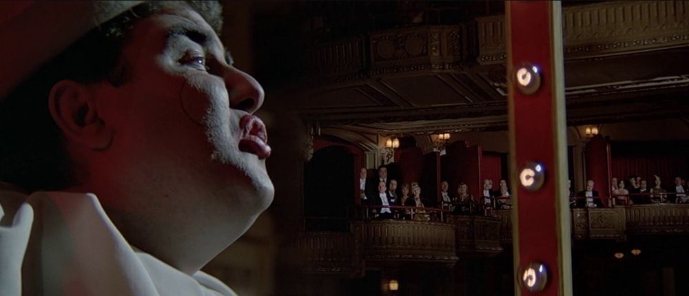 Split-diopter shot from The Untouchables showing Pagliacci the clown in the foreground and Al Capone in the background. Both perfectly in focus.