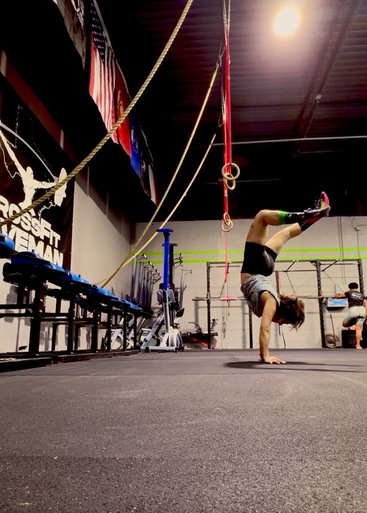 Wonky handstand by a woman at the gym. Legs bent and body leaning. 