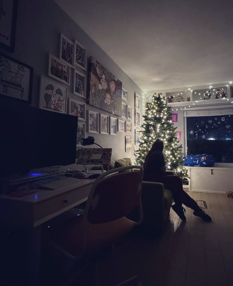 Silhouette of woman in front of Xmas tree, her dark desk on the side. 