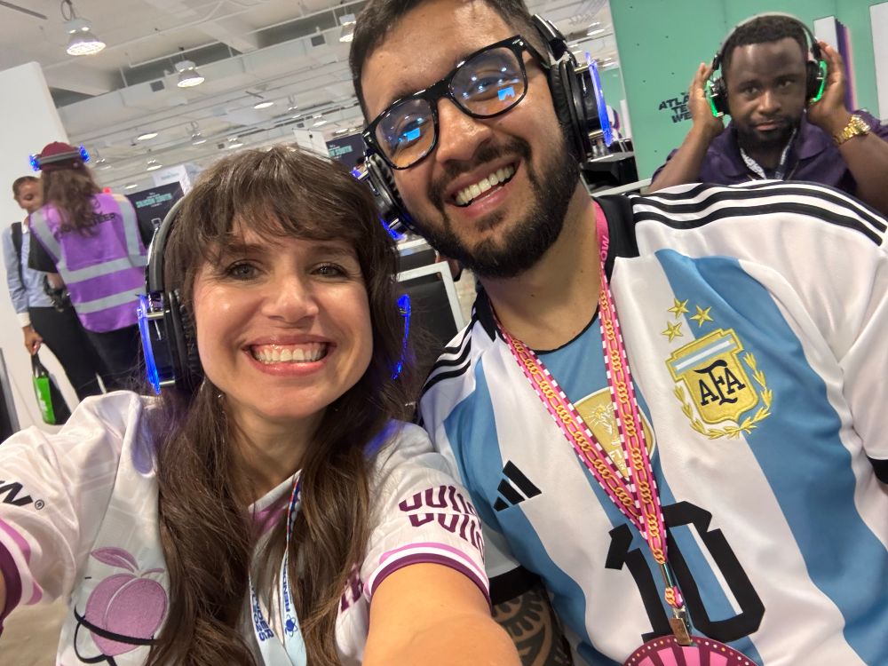 Two people wearing headphones, smiling at the camera
