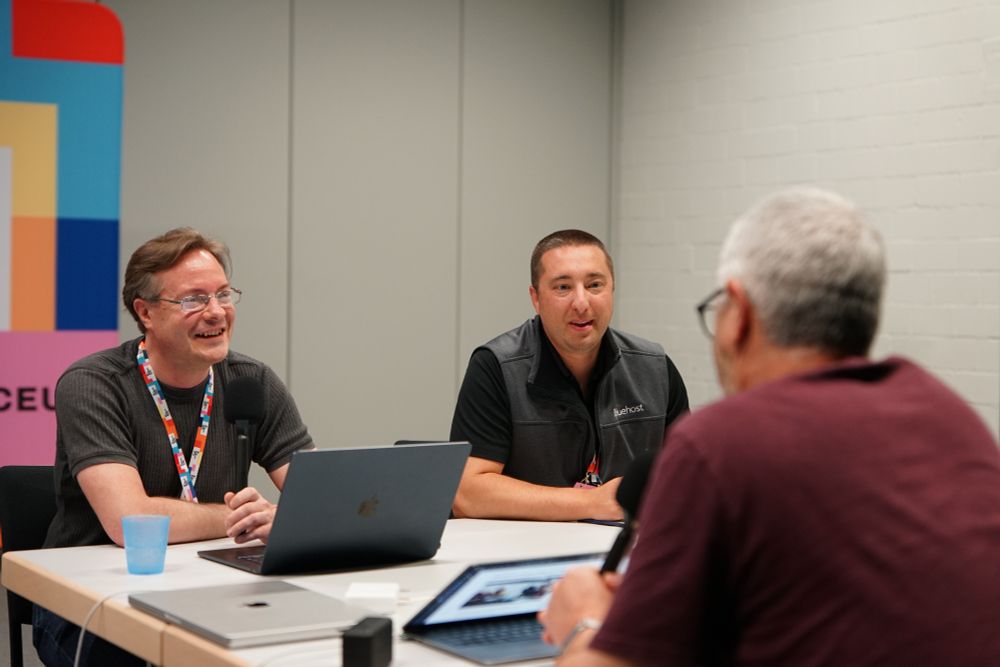 Jonathan and Joe laughing and talking to Nathan, who's back is to the camera and is out of focus in the foreground. Photo credit: Roberto Vázquez (https://www.flickr.com/photos/wceu/54571191300/).