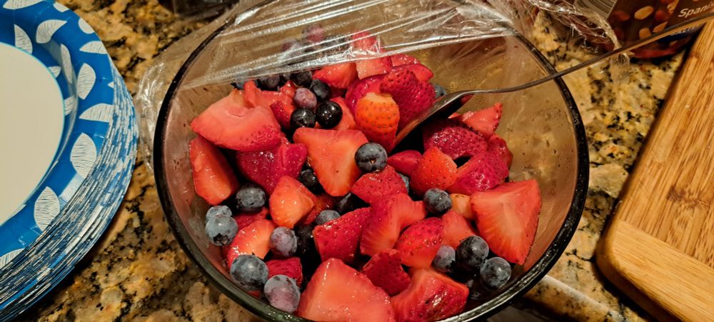 A combination of strawberries and blueberries in a glass bowl.