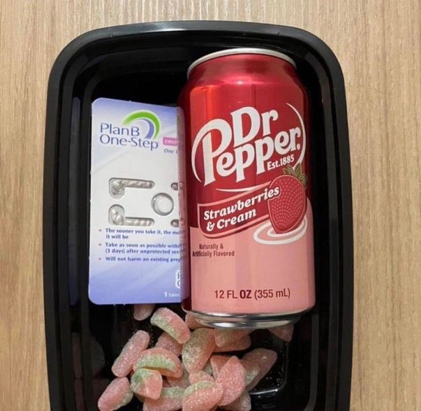 A takeout box with plan b, a can of Dr Pepper strawberries and cream, and watermelon sour patches. It’s on a plywood table. 