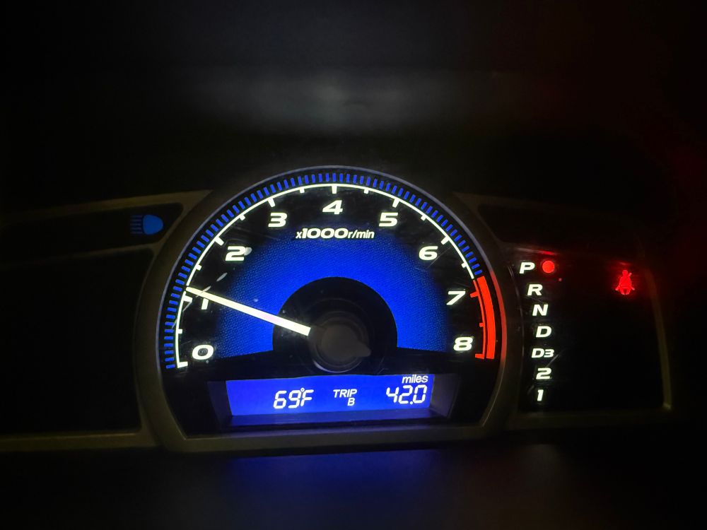 A car dashboard shows that it is 69 degrees Fahrenheit and shows a trip odometer of 42.0 miles. The car is safely in park!