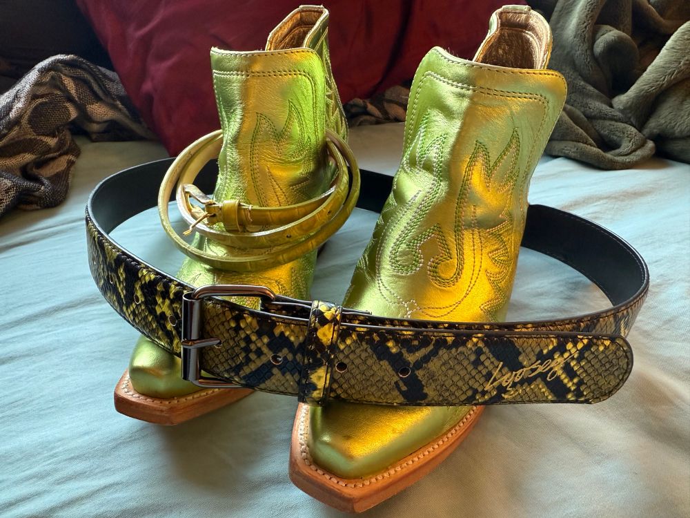 Detailed shimmery lime green cowboy ankle boots with two different belts that match. One belt is skinny and solid green, the other is wider and a black and green snake pattern.