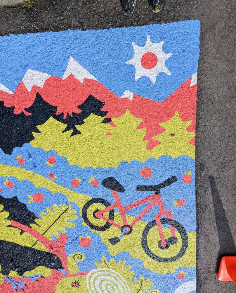closer shot of the mural showing a bike, strawberry bushes, and pines and mountains
