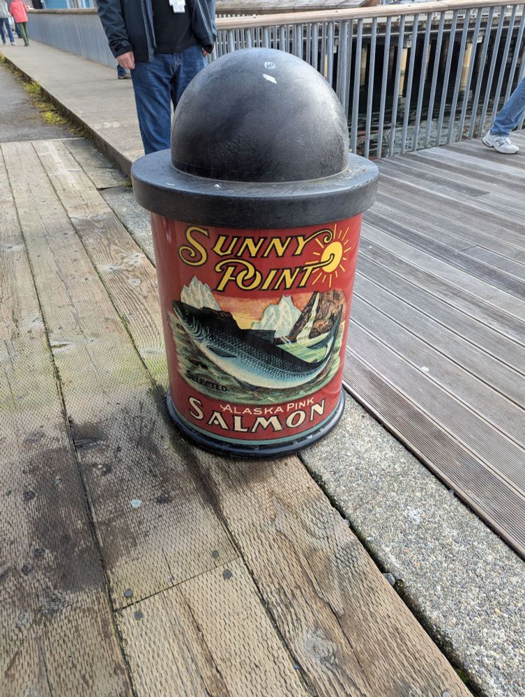 A photo of a trashcan decorated with a vintage canned salmon label