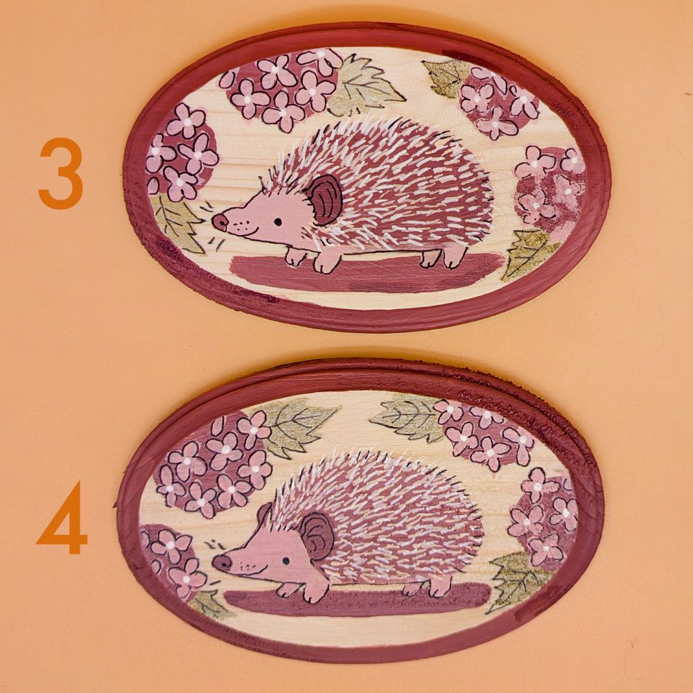 two plaques featuring hedgehogs & lilacs in a reddish color with shiny leaves