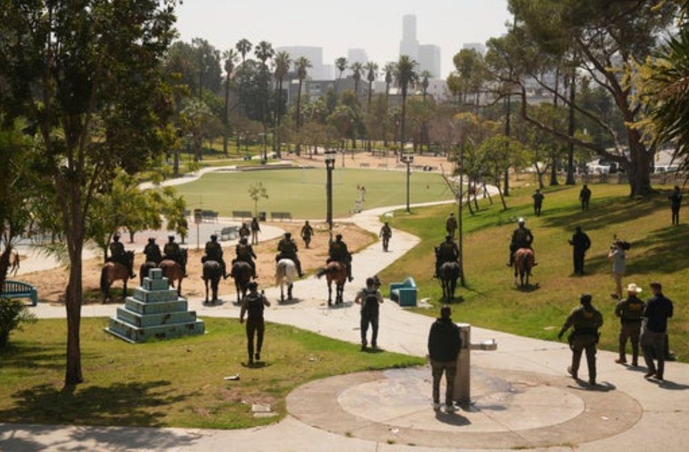 Federal officers descending on foot and horseback into MacArthur Park in Los Angeles.
Photo credit:  AP Photo/Damian Dovarganes