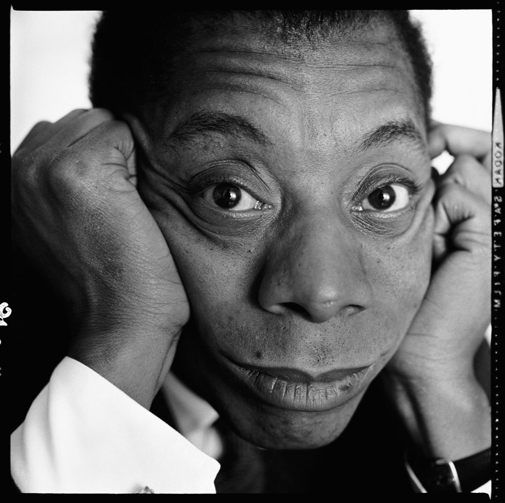 Black and white portrait of James Baldwin, showing his face perched between his two hands, looking wide-eyed toward the camera. 

Photograph by Richard Avedon, taken in 1962
