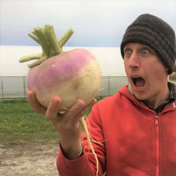 Dan Brisbois holding a giant turnip and with amazed look on his face.
