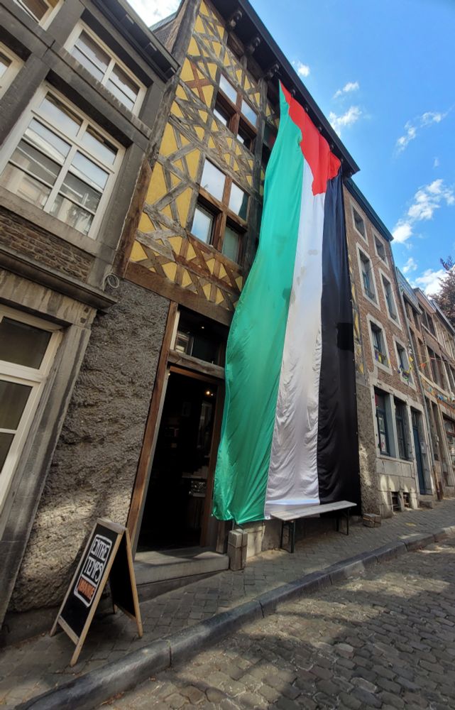 Façade de la librairie largement recouverte d'un drapeau palestinien de 10 mètres de haut.