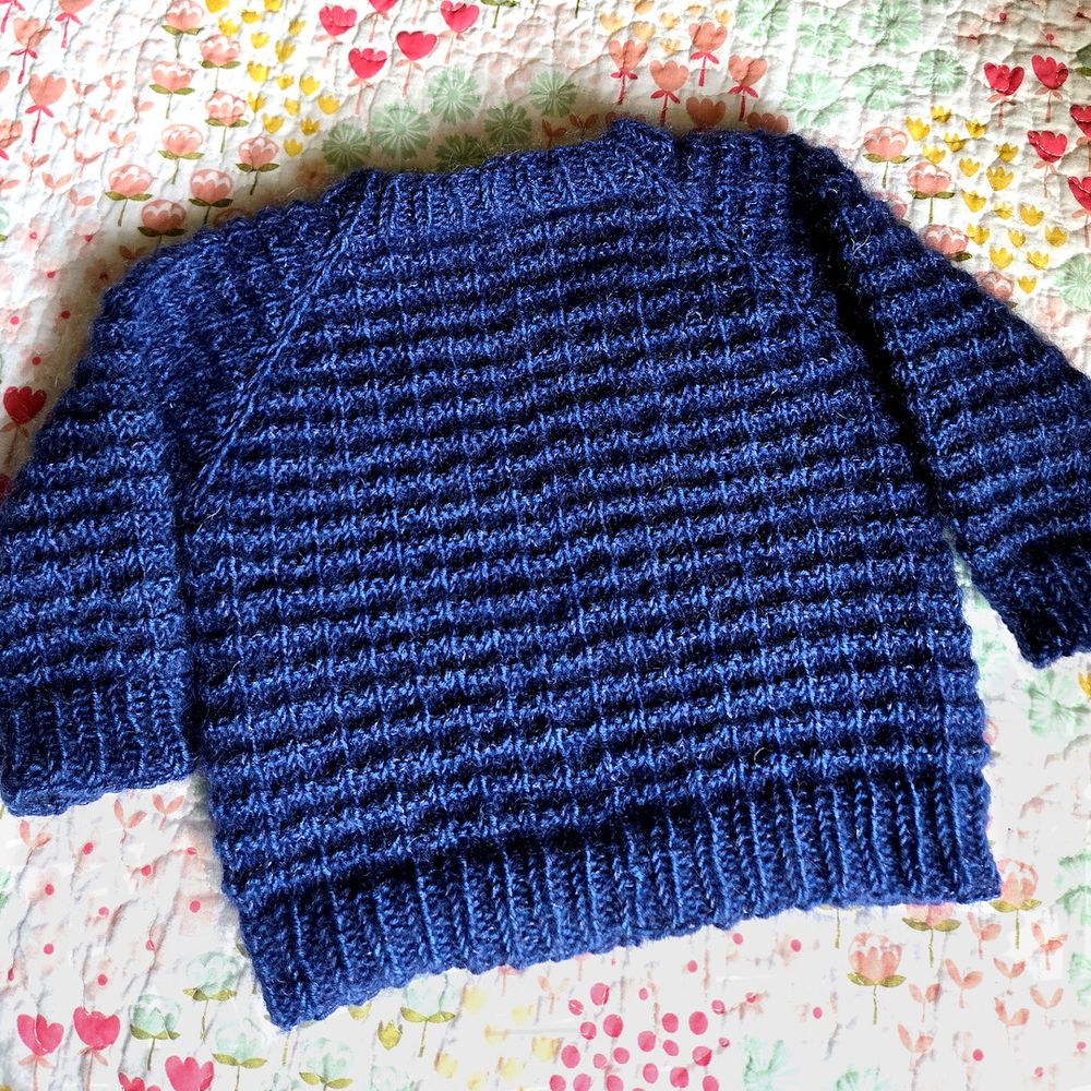 Top down hand knitted child's pullover with raglan sleeves and textured body.