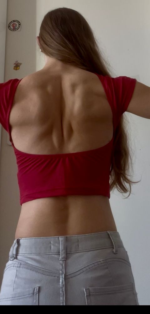 Foto von hinten, man sieht den oberen Rand meiner Jeans, ein rückenfreies rotes Oberteil, angespannte Rückenmuskulatur und meine Haare, die seitlich über die Schulter fallen 