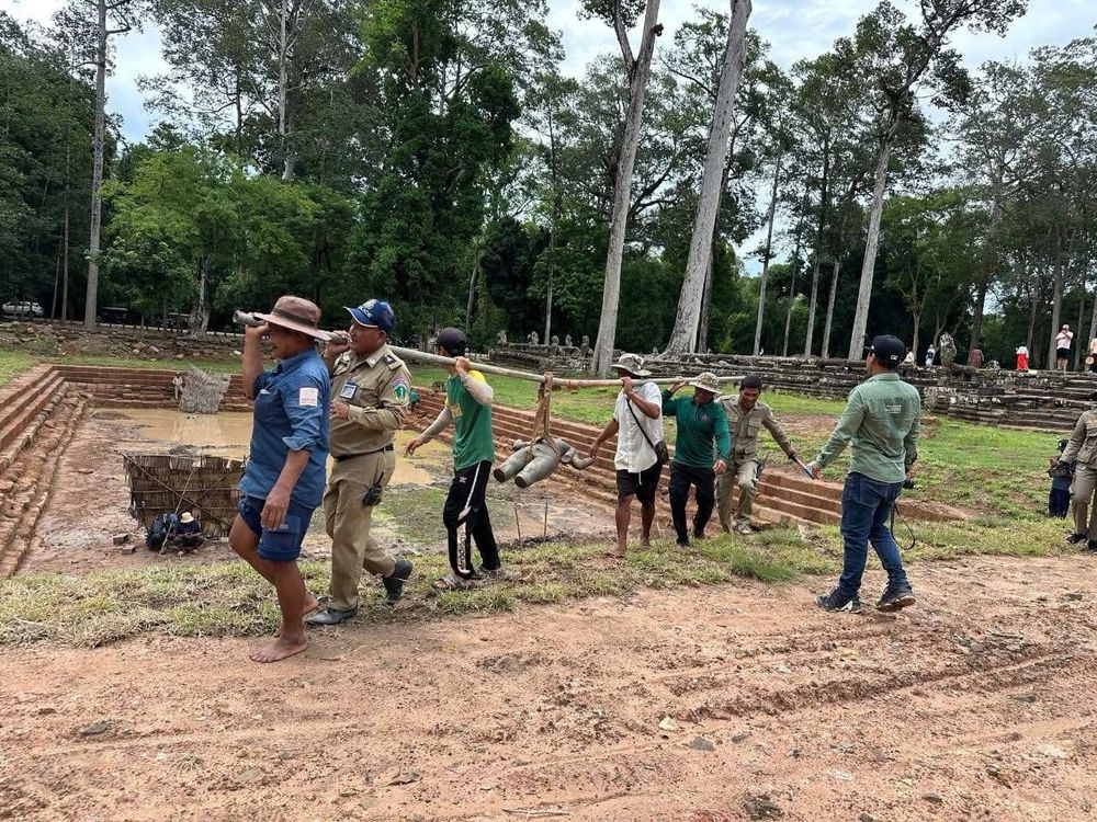 Workers carrying the stone deity from the 12/13th century at the Bayon temple at Angkor Thom.