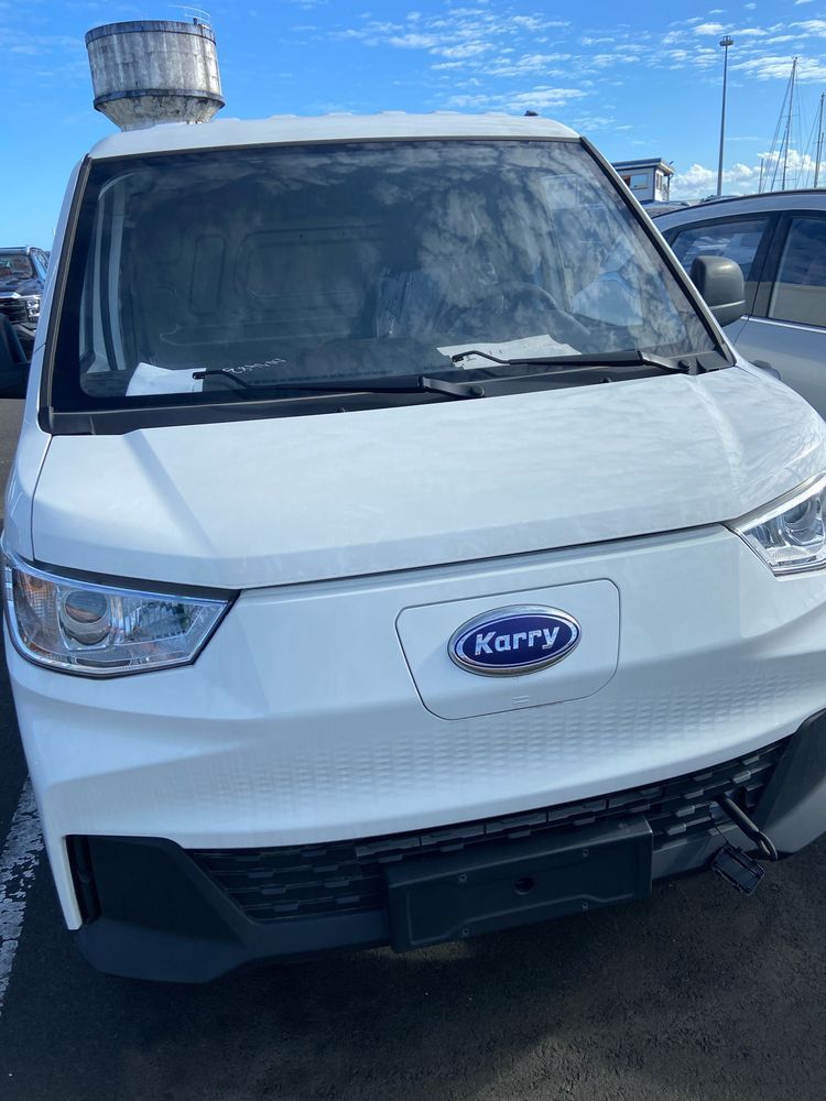 A white electric delivery van with a blue oval logo with the name Karry written inside.