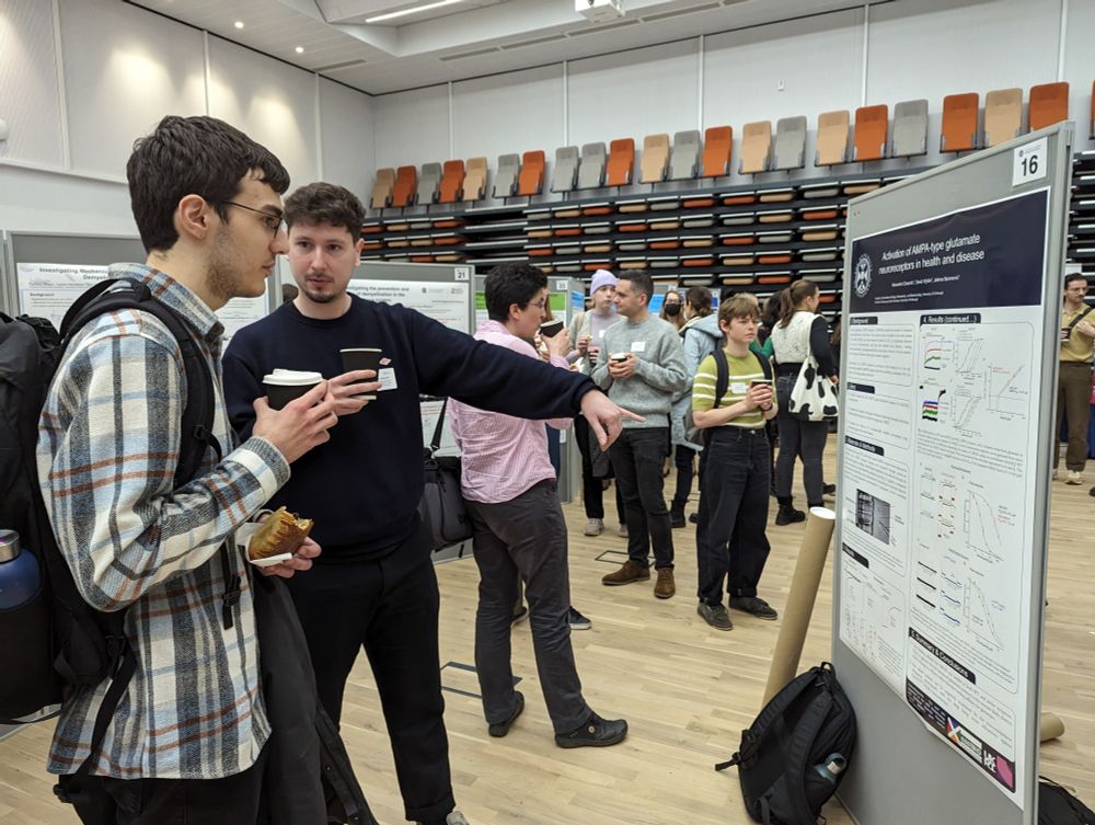 Photo of researchers interacting beside a poster display