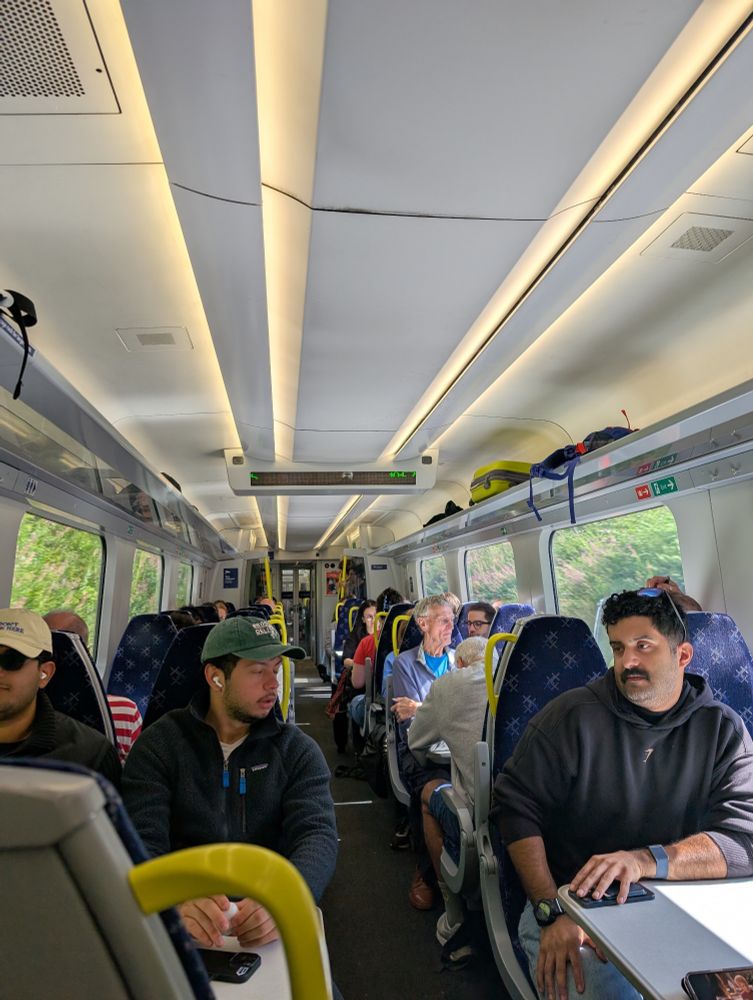 View looking down the aisle on board a ScotRail train, with passengers occupying almost every seat.