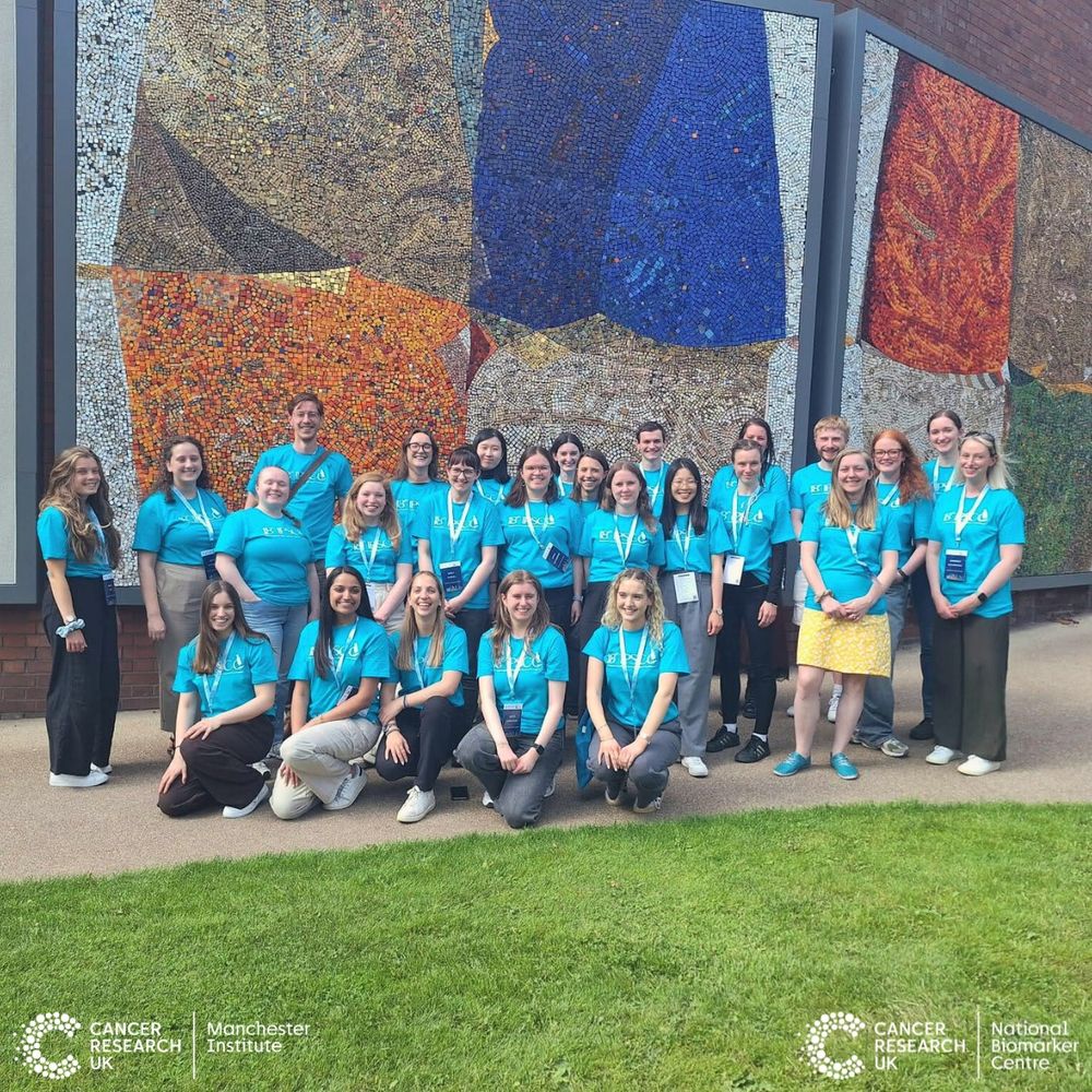 Photograph shows the whole organising committee outside in front of a large mosaic mural
