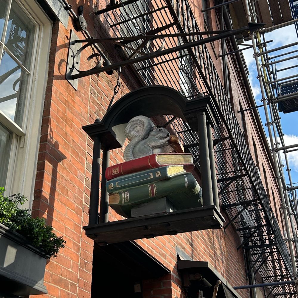 Hanging sign for the bookshop showing a stack of books and a squirrel